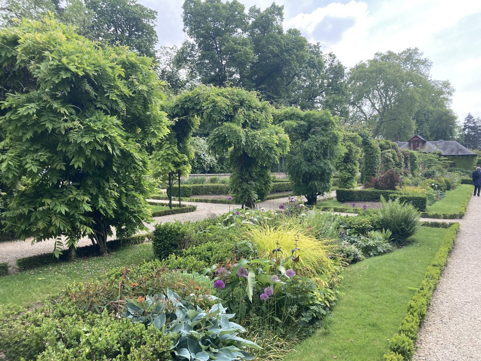 Frodig blomsterhage med roser og klipte plener i Parc de Bagatelle