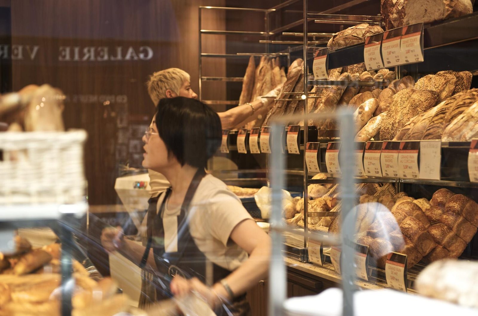 Salgsdisk i et bakeri i Paris med baguetter og bakverk bak glass