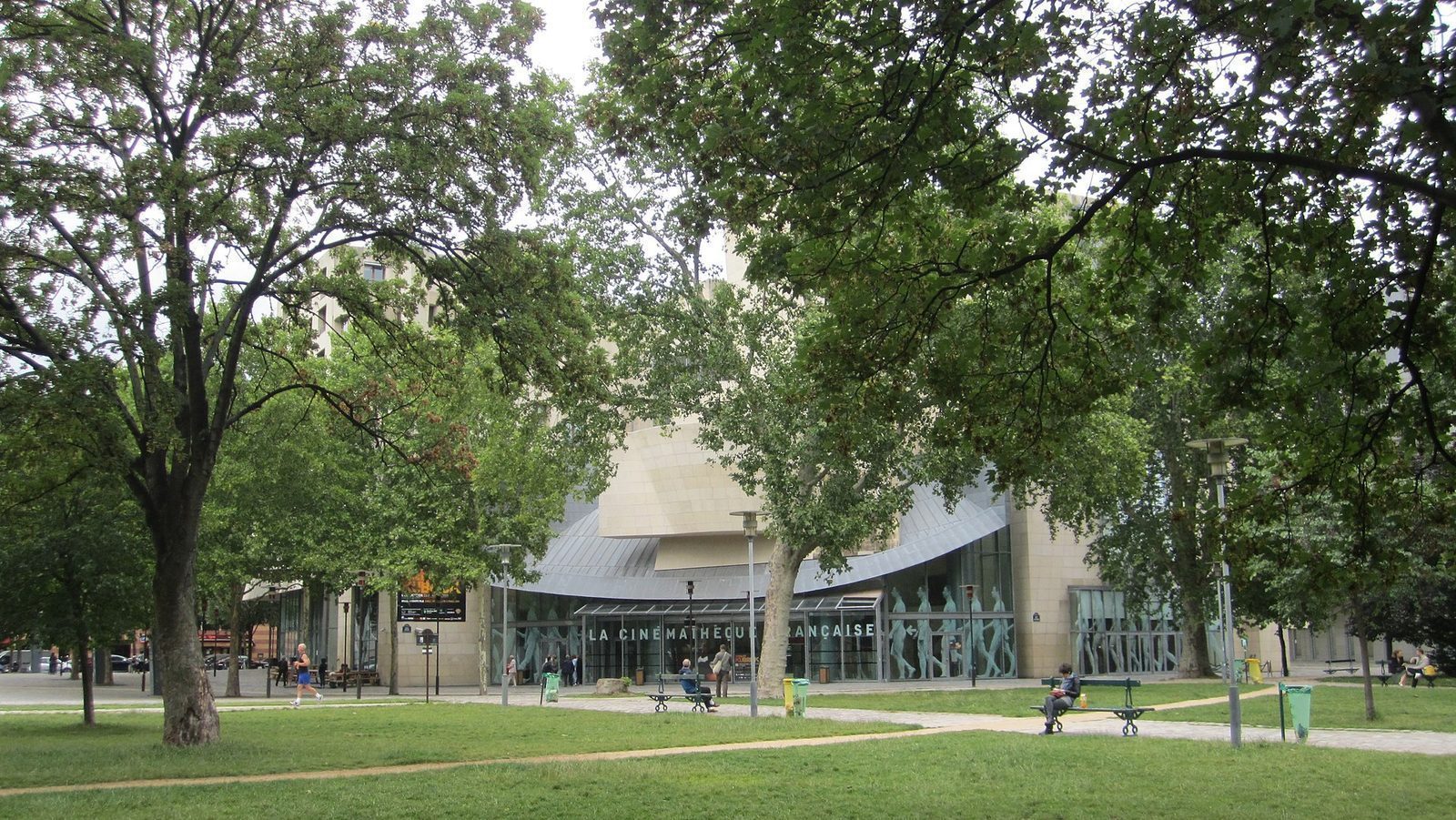 Frank Gehrys skjeve bygning i lys kalkstein og glass med skiltet La Cinémathèque française, sett fra Parc de Bercy