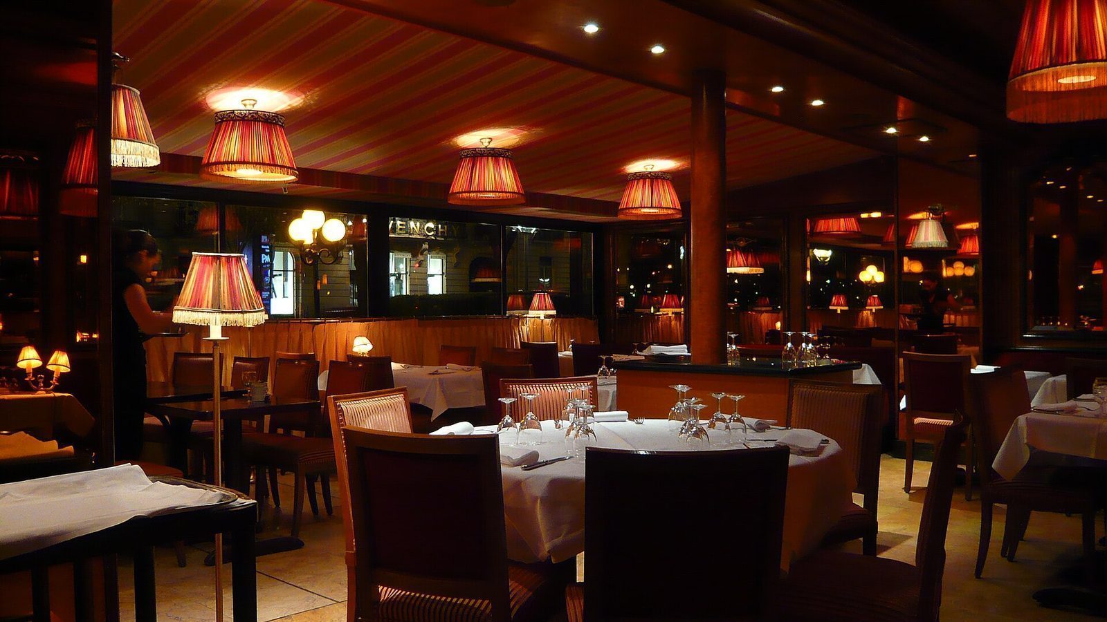 Interiør i en parisisk brasserie med hvite duker, speil og lampeskjermer i rødt