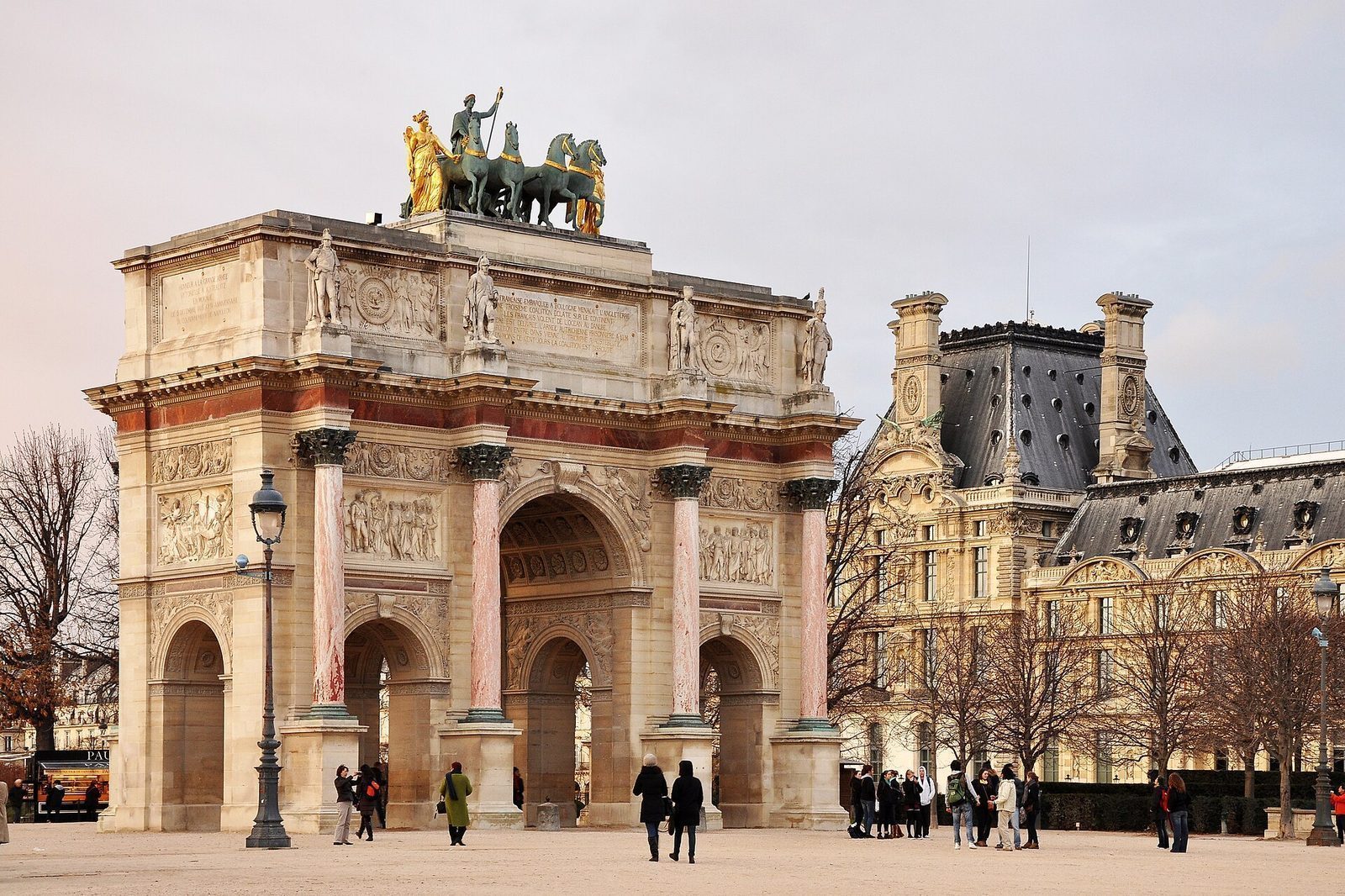 Arc de Triomphe du Carrousel i rosa marmor og lys stein, med Louvre-fløyen i bakgrunnen