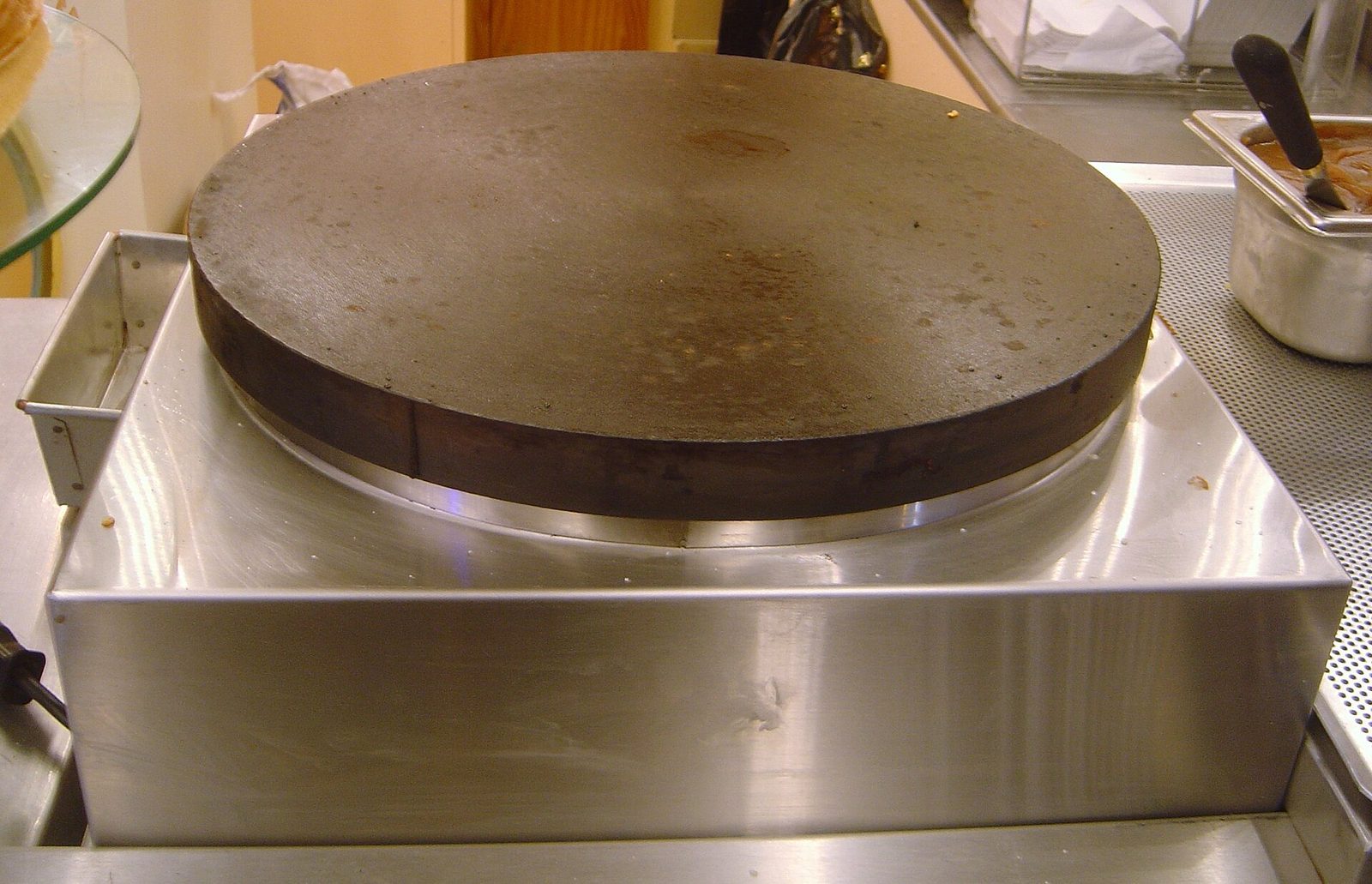 Rund støpejernstakke til crêpes på en varmeplate i en crêperie