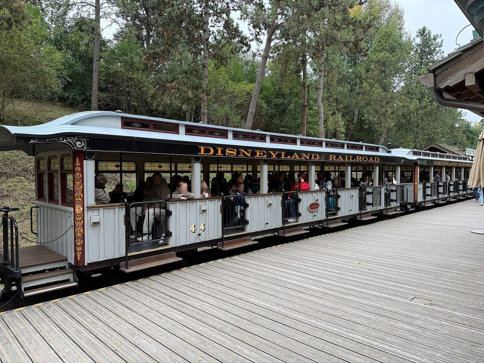 Toget Disneyland Railroad står ved perrongen med passasjerer i åpne vogner