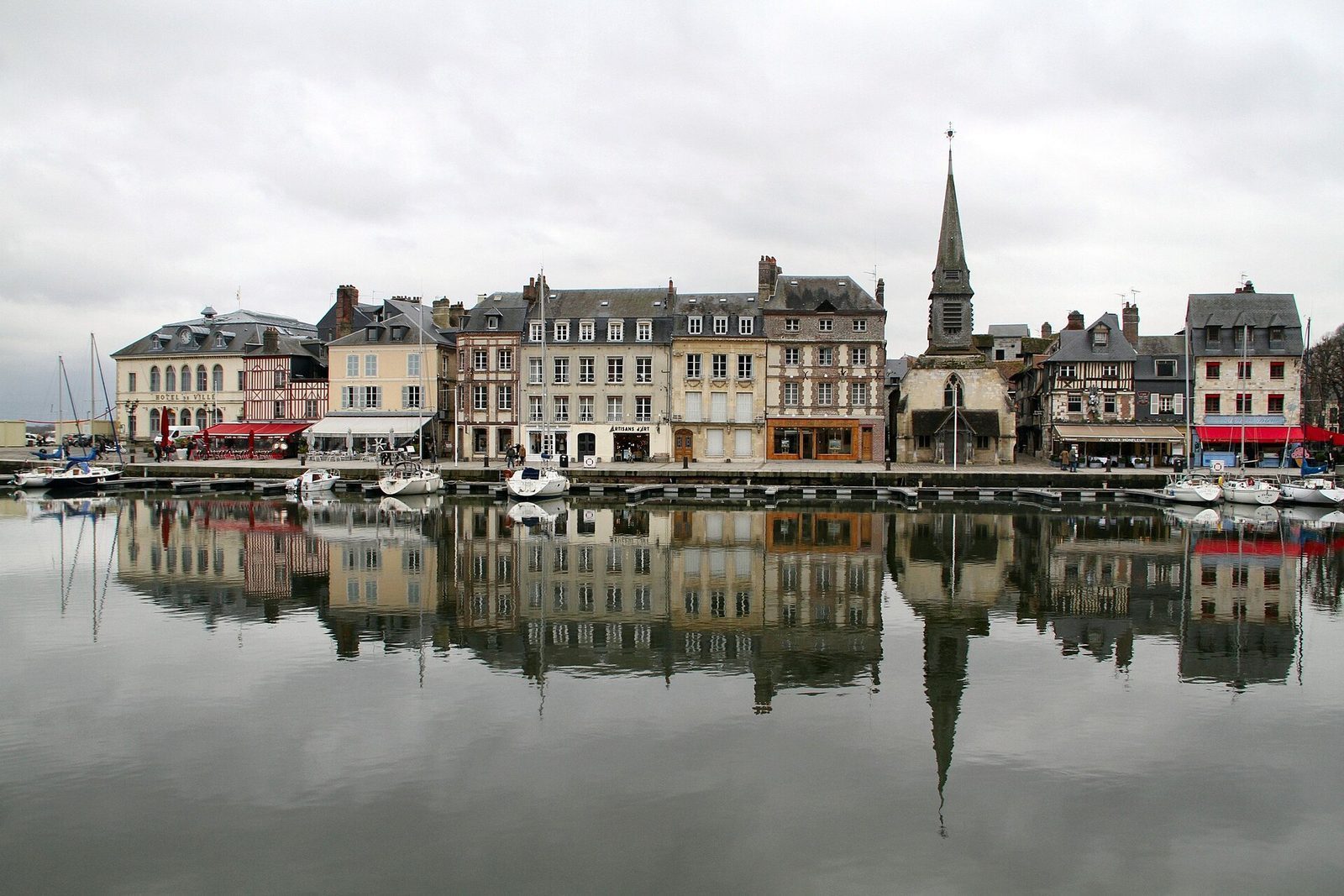 Smale skifertekte hus speiler seg i den gamle havnebassenget Vieux Bassin i Honfleur