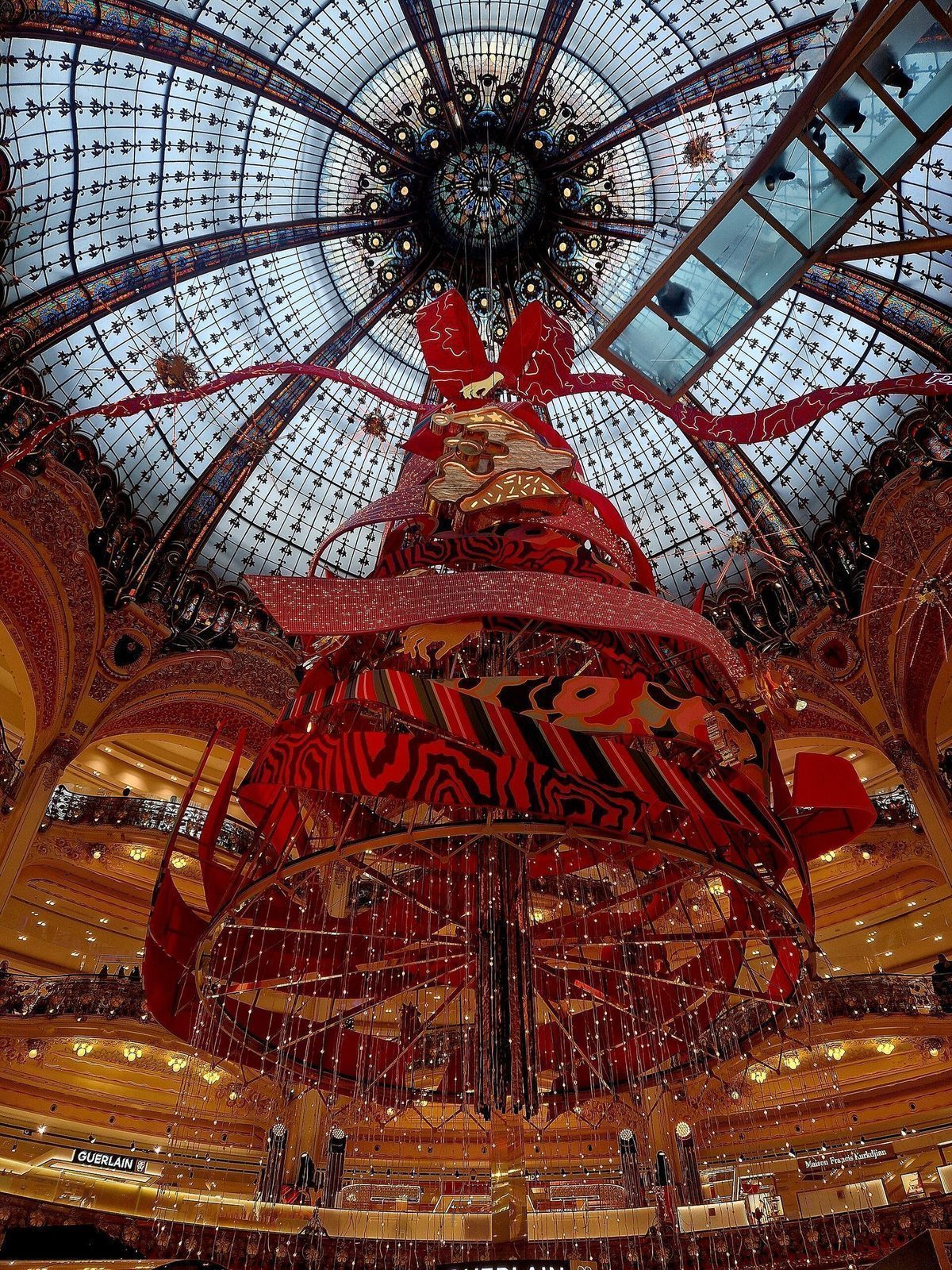 Det store juletreet i rødt henger under glasskuppelen i Galeries Lafayette, omkranset av forgylte balkonger