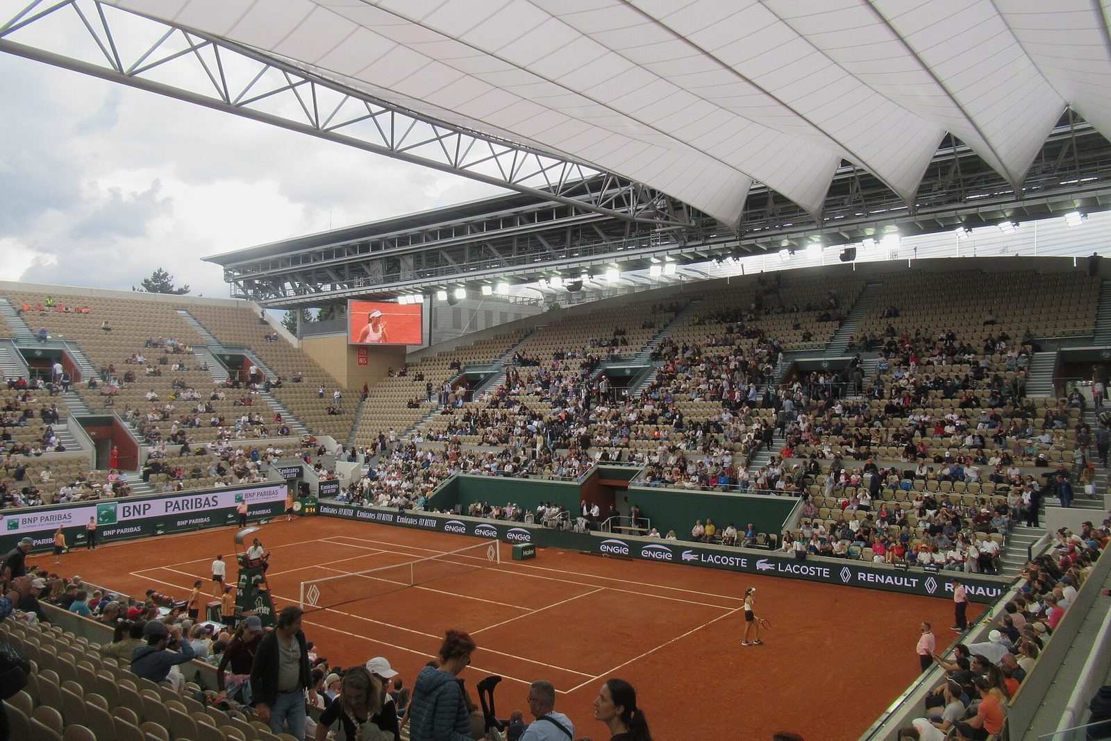 Court Suzanne-Lenglen med grusbane, fullsatte tribuner og det utfellbare taket delvis trukket ut