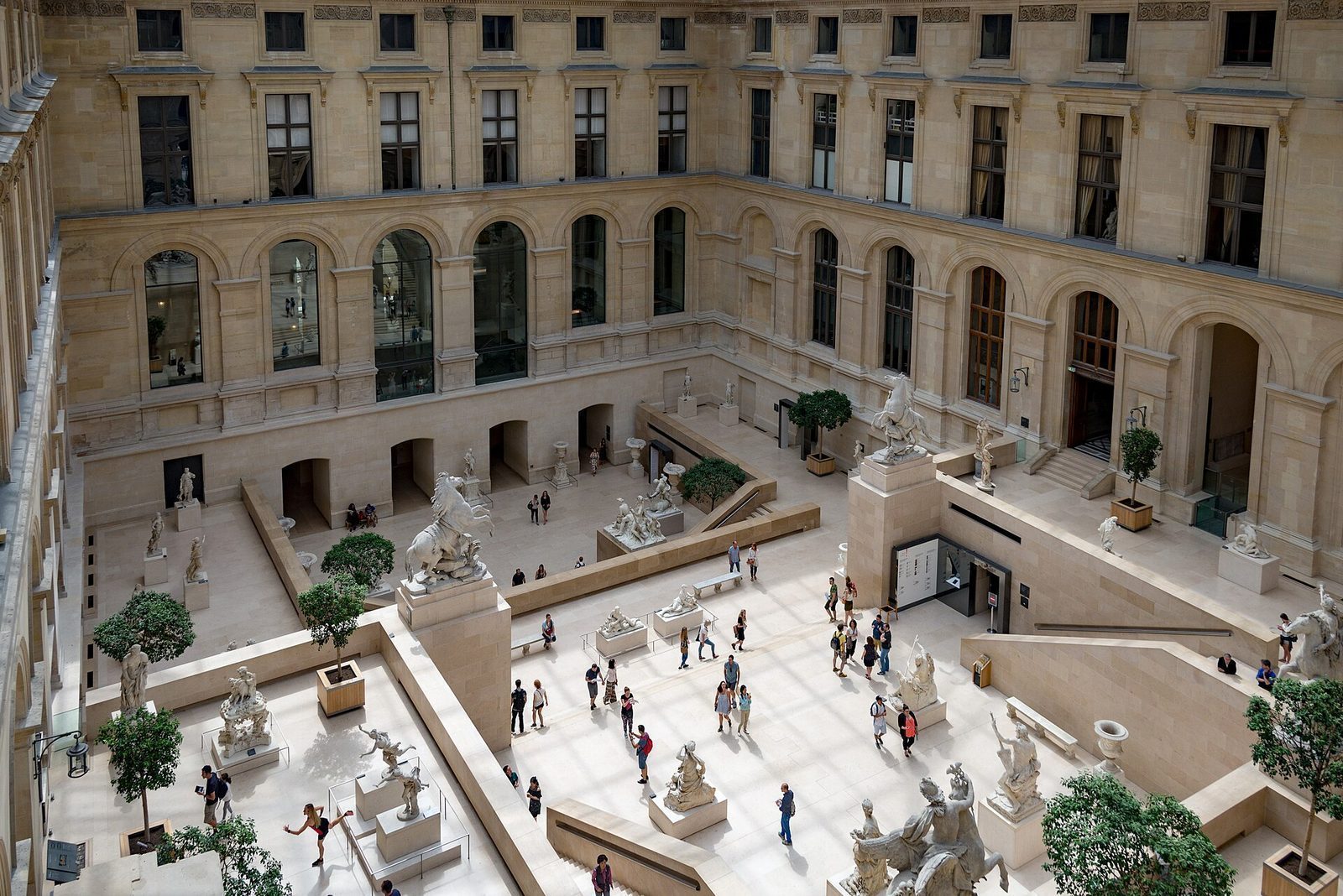 Den glassoverbygde gårdsplassen Cour Marly i Louvre med hvite marmorskulpturer på flere nivåer