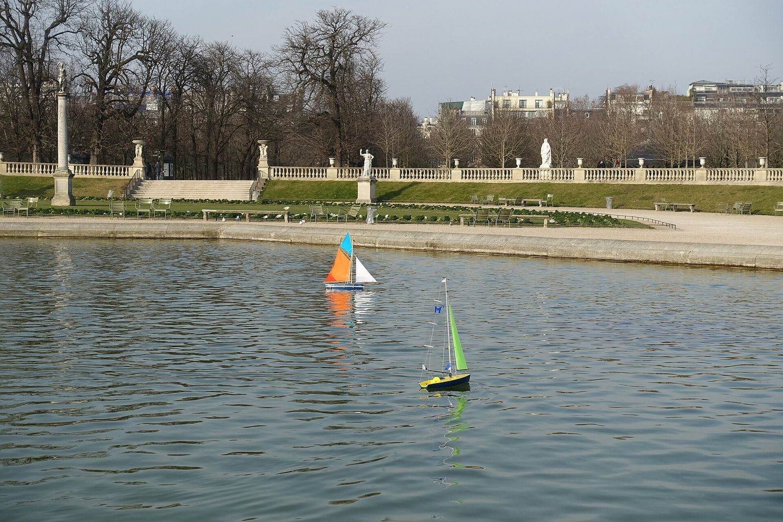 Modellseilbåter på den runde dammen i Jardin du Luxembourg med grønne stoler rundt