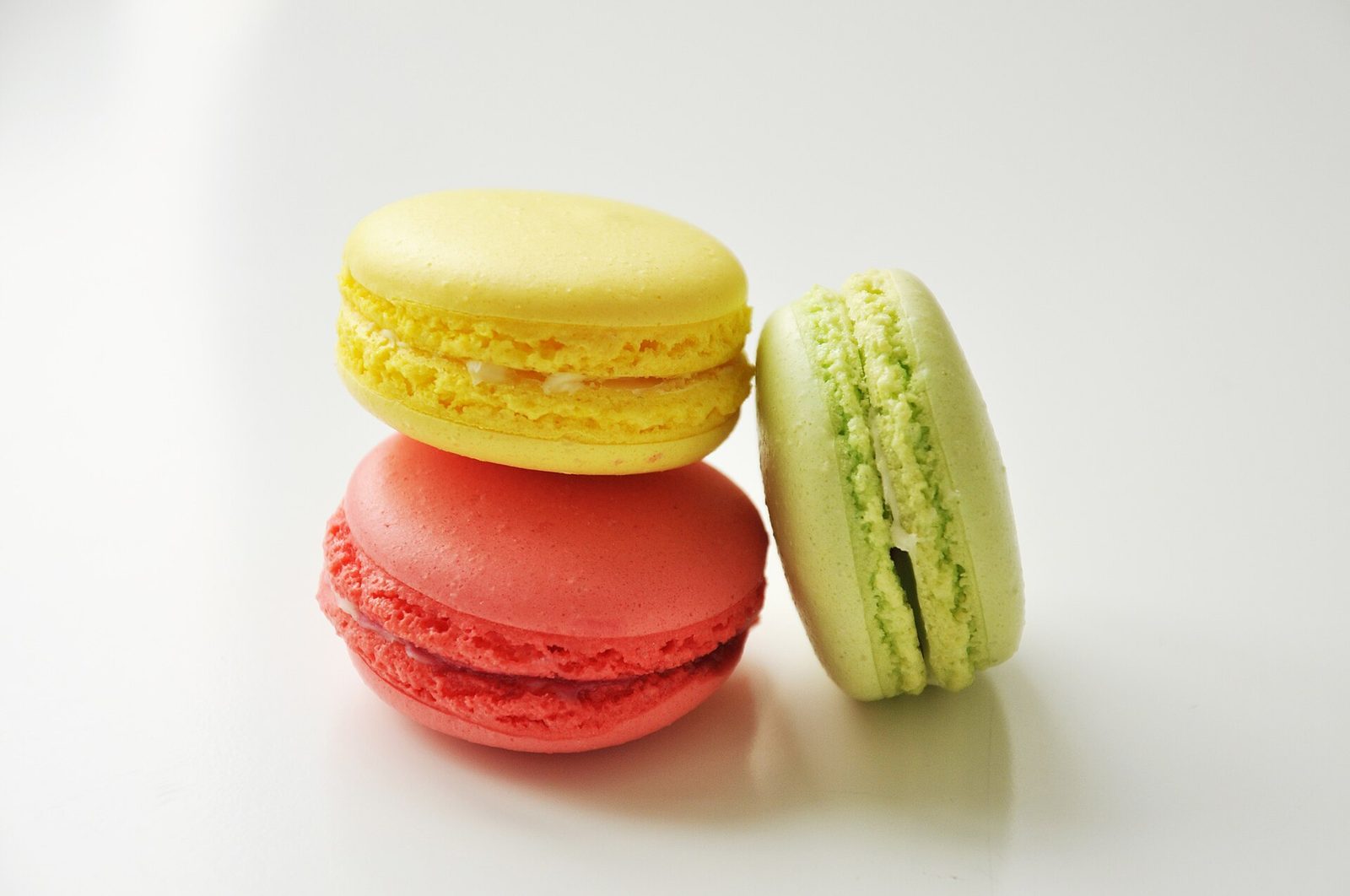 Tre macarons i lyse farger på hvitt underlag