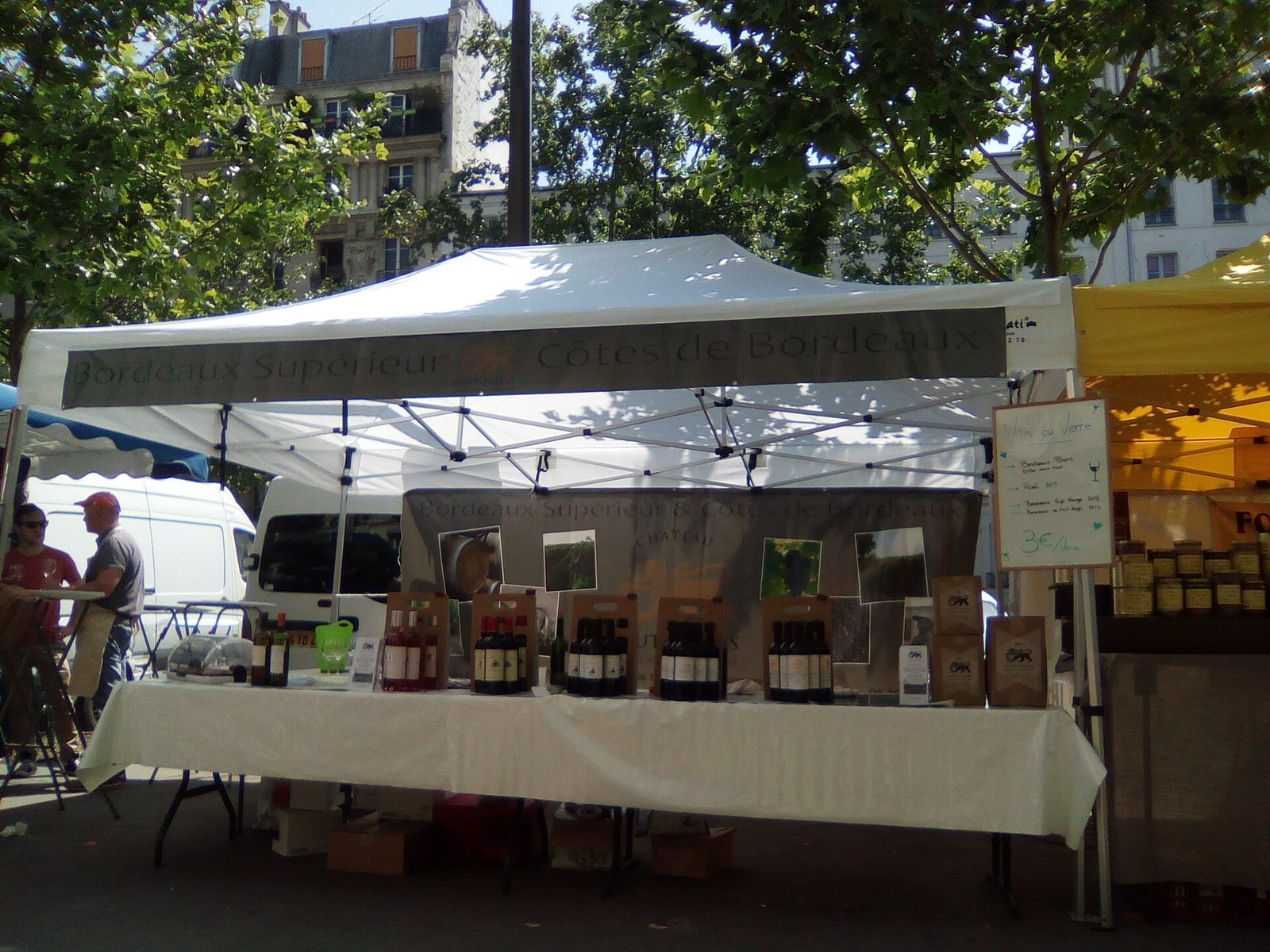 Vinbod med bordeauxflasker under hvitt telttak på et gatemarked i Paris