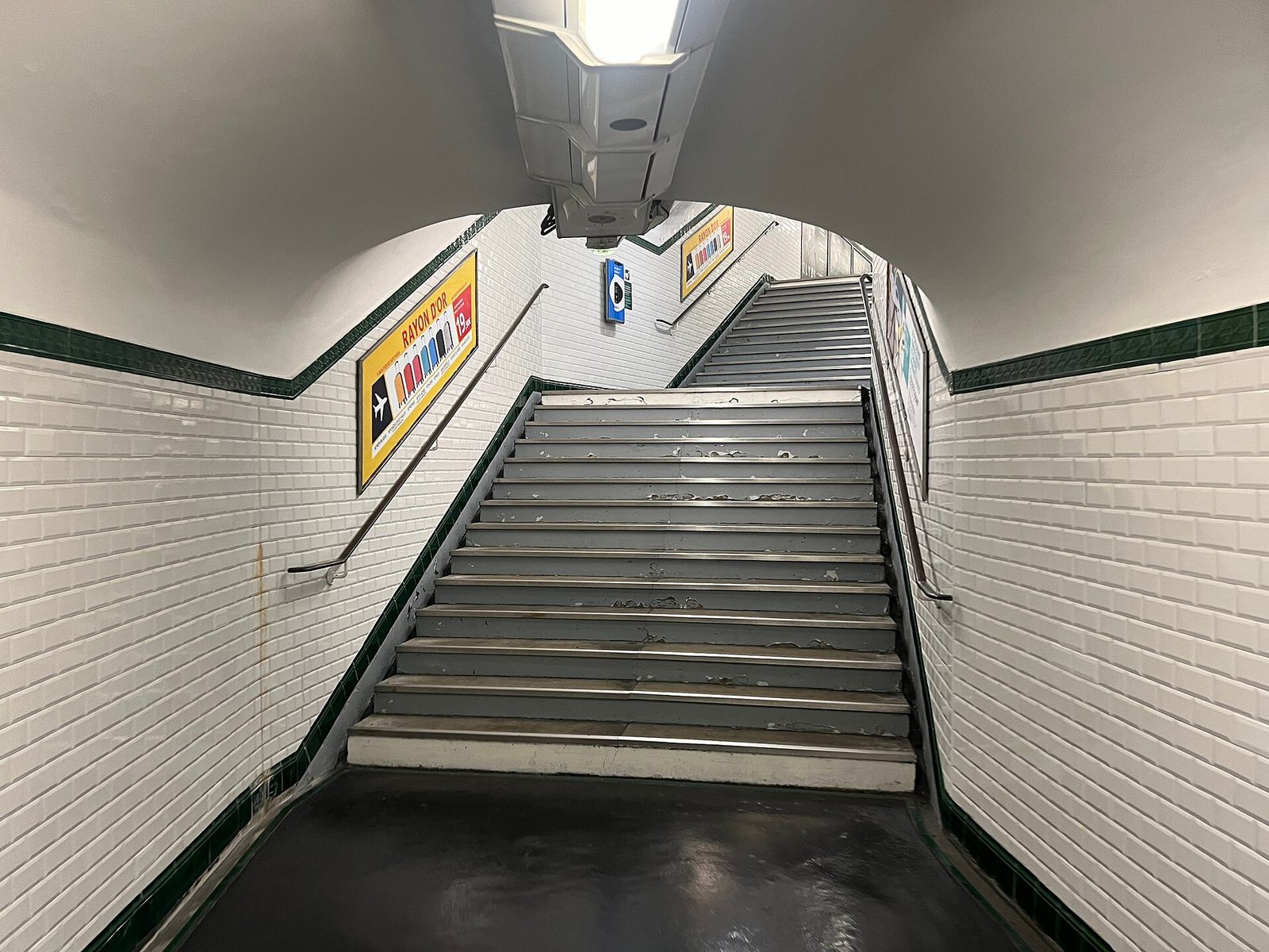 To bratte trappeløp i en hvitflislagt gang på metrostasjonen République, uten heis eller rulletrapp