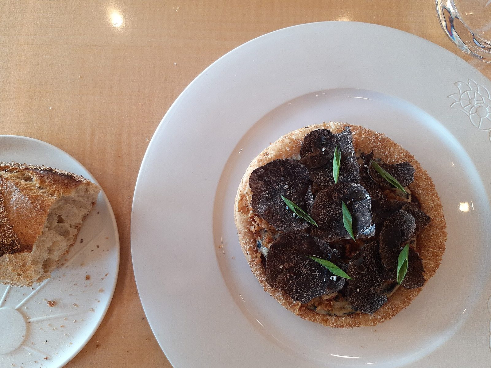 Forrett med tynne skiver svart trøffel på en liten terte, servert med brød