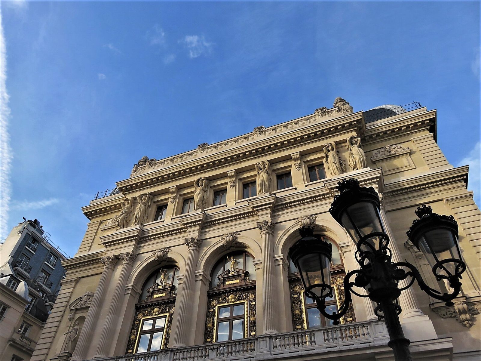Fasaden til Opéra Comique i Paris med buer, søyler og statuer