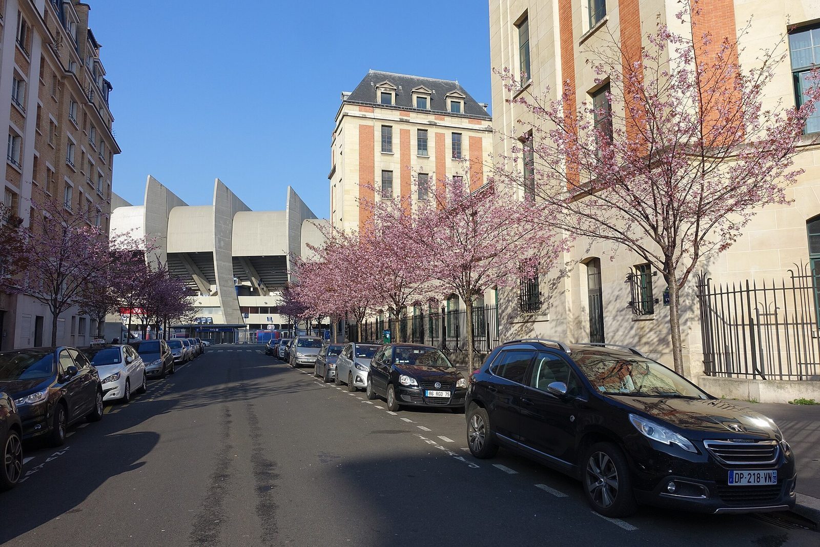 Parc des Princes' betongribber sett fra en gate i 16. arrondissement med blomstrende kirsebærtrær