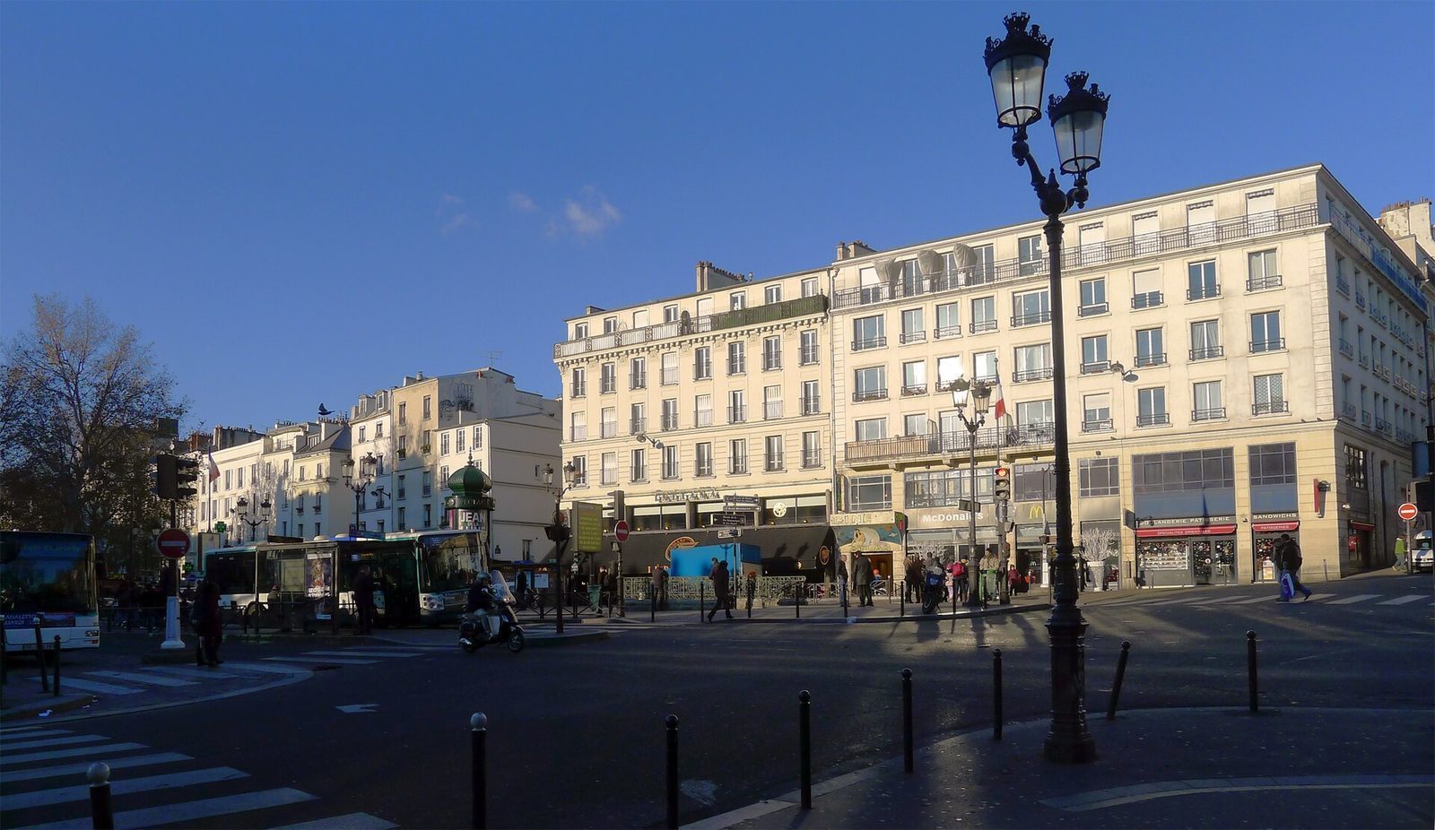 Place Pigalle i dagslys med metronedgang, bygårder og folk som krysser gaten