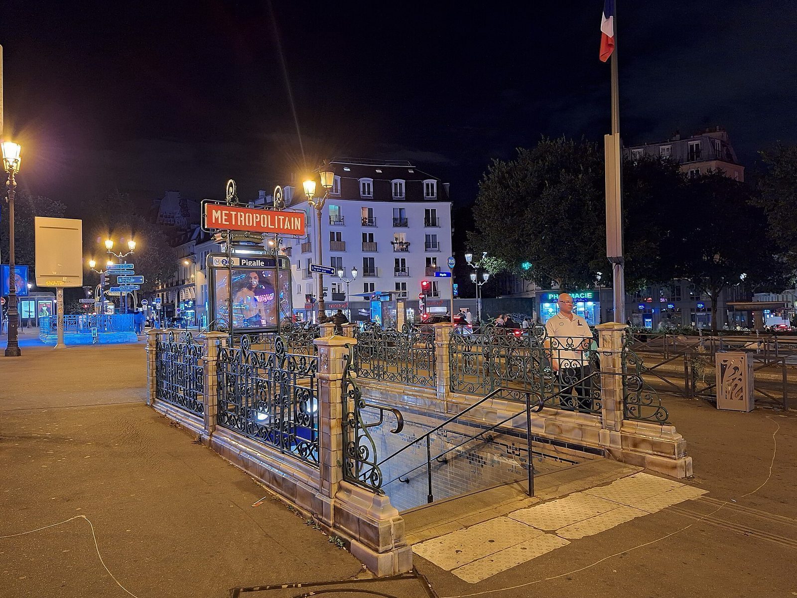Opplyst metronedgang med Métropolitain-skilt på Place Pigalle om natten