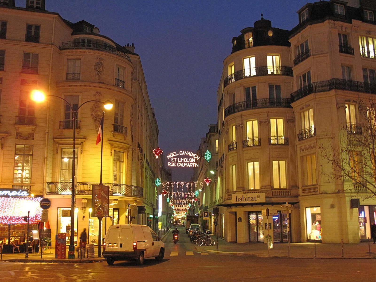 Rue de Caumartin i skumringen med julelys spent over gaten, opplyste butikkvinduer og våt asfalt