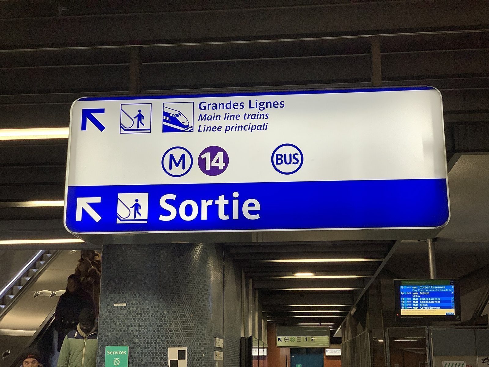 Opplyst skilt i RER-stasjon som viser vei til Sortie, Grandes Lignes, metro 14 og buss