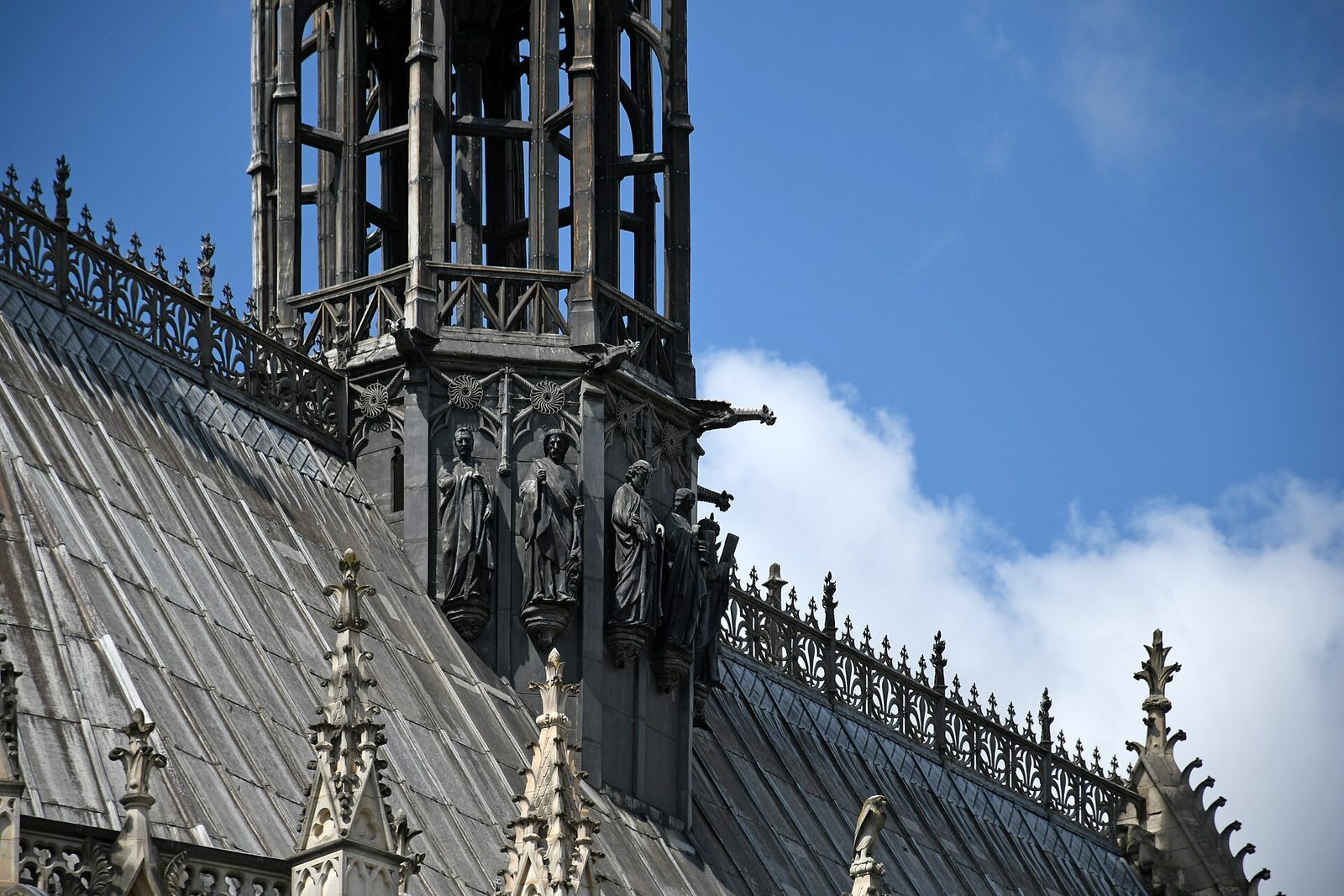 Taket og spiret på Sainte-Chapelle med apostelfigurer og gjennombrutt steinbalustrade mot blå himmel