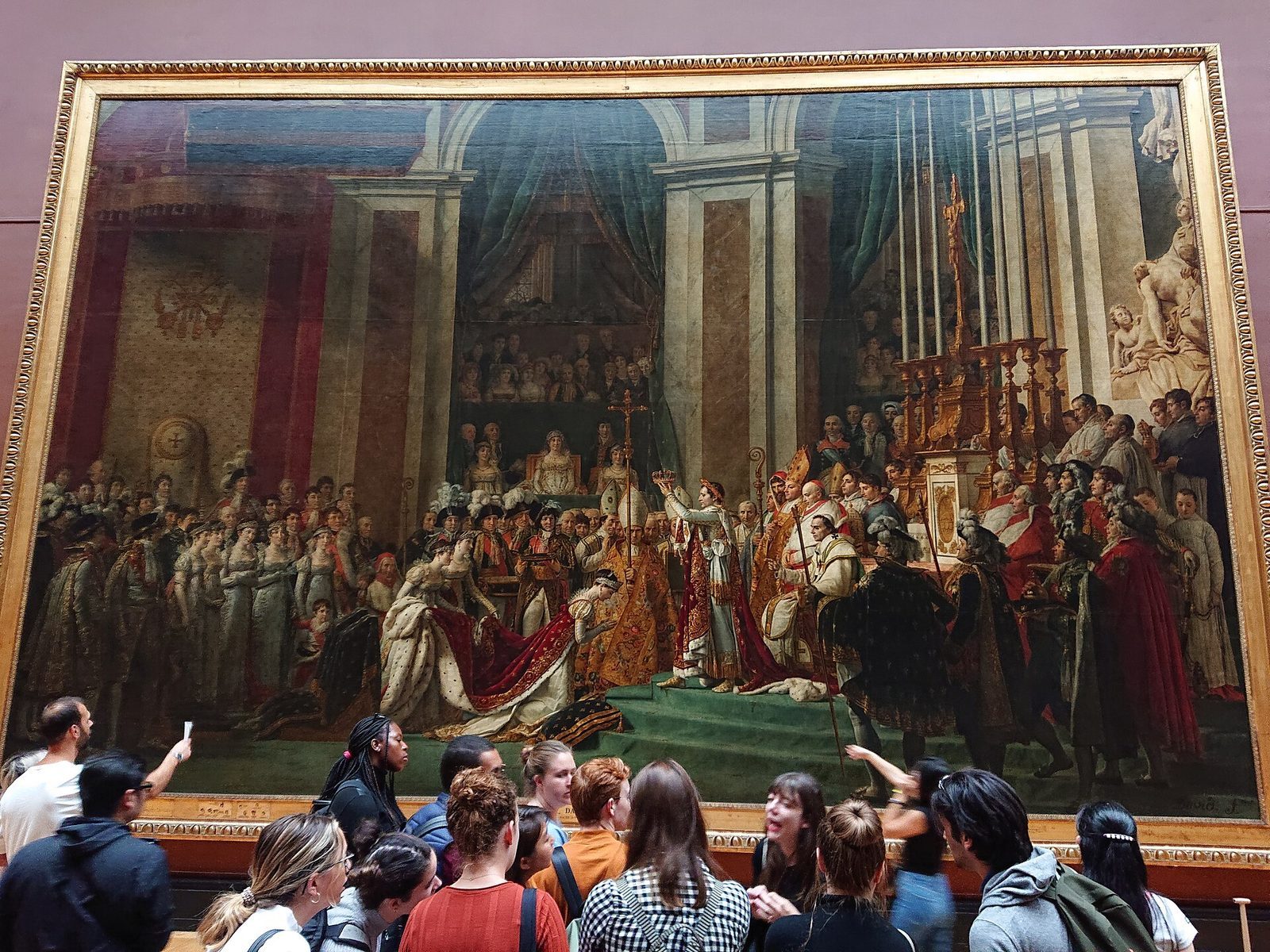 Tett med besøkende foran et stort historiemaleri i en sal i Louvre