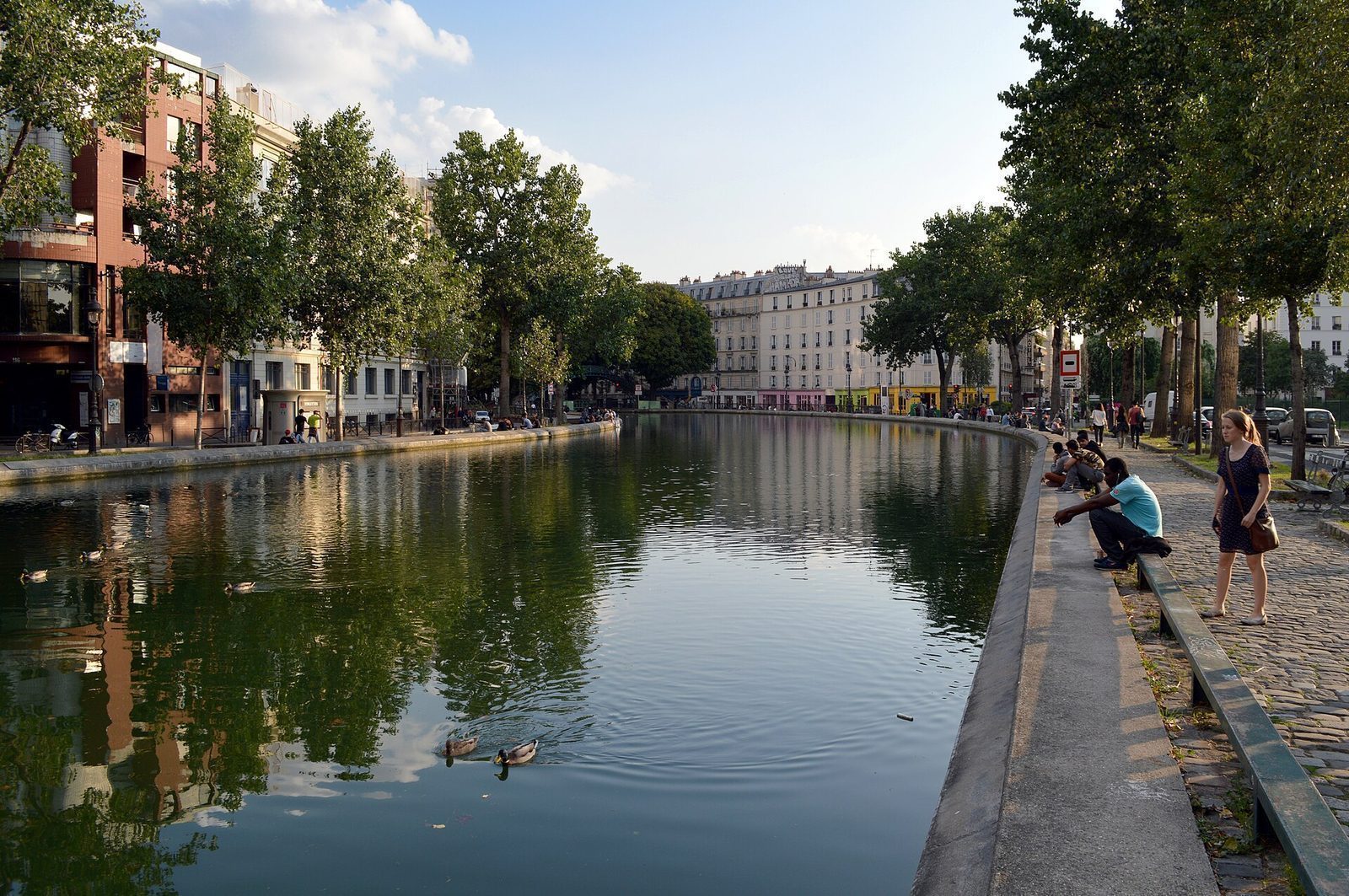 Canal Saint-Martin sett fra Quai de Valmy, med platantrær langs begge kaier og folk ved vannkanten