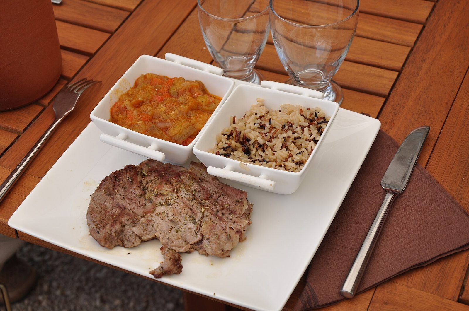 Grillet lammekjøtt servert med ratatouille og ris på en fransk restaurantterrasse