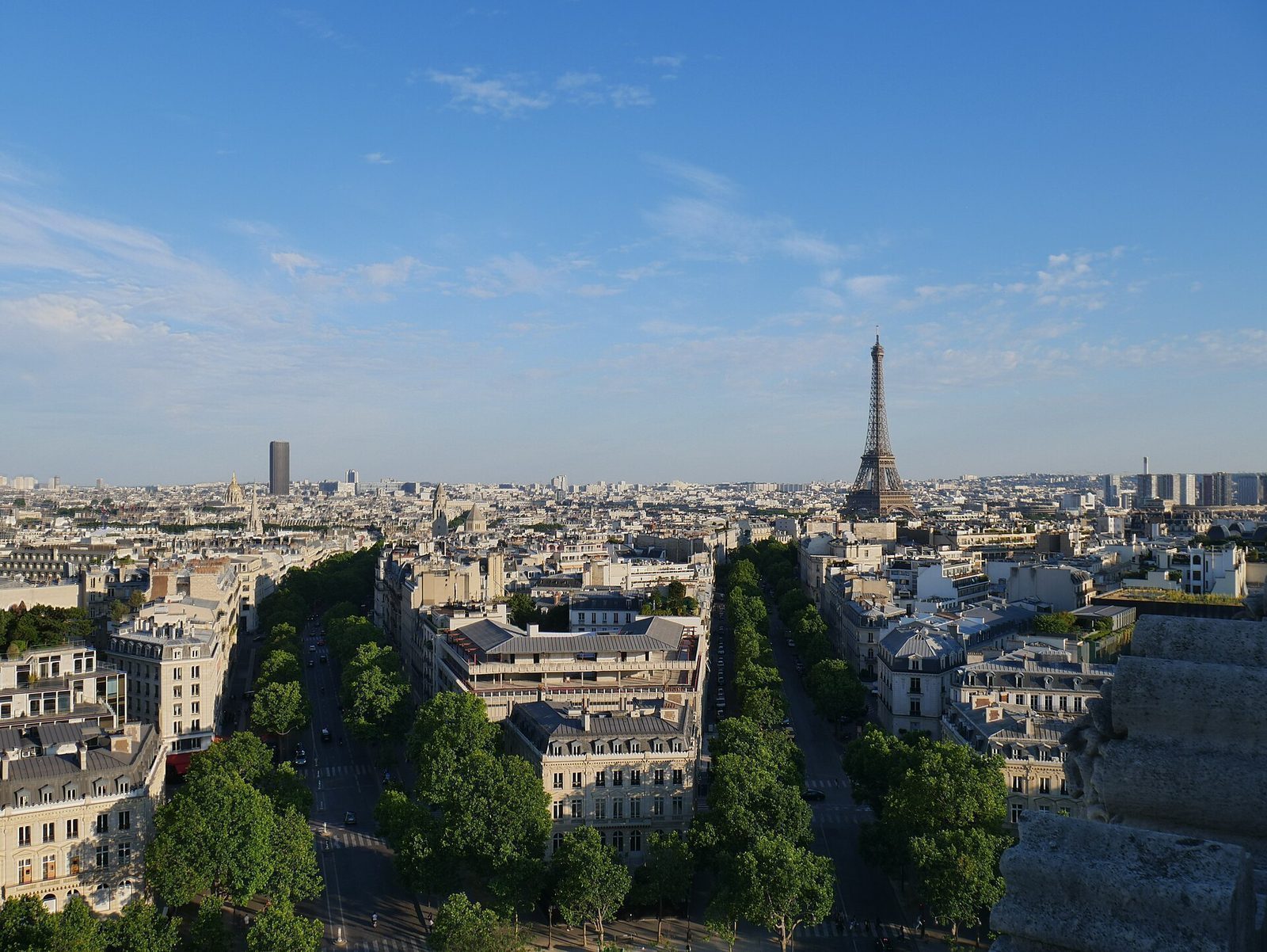 Utsikt fra taket av Triumfbuen mot Eiffeltårnet og Tour Montparnasse over Paris' takåser i klarvær