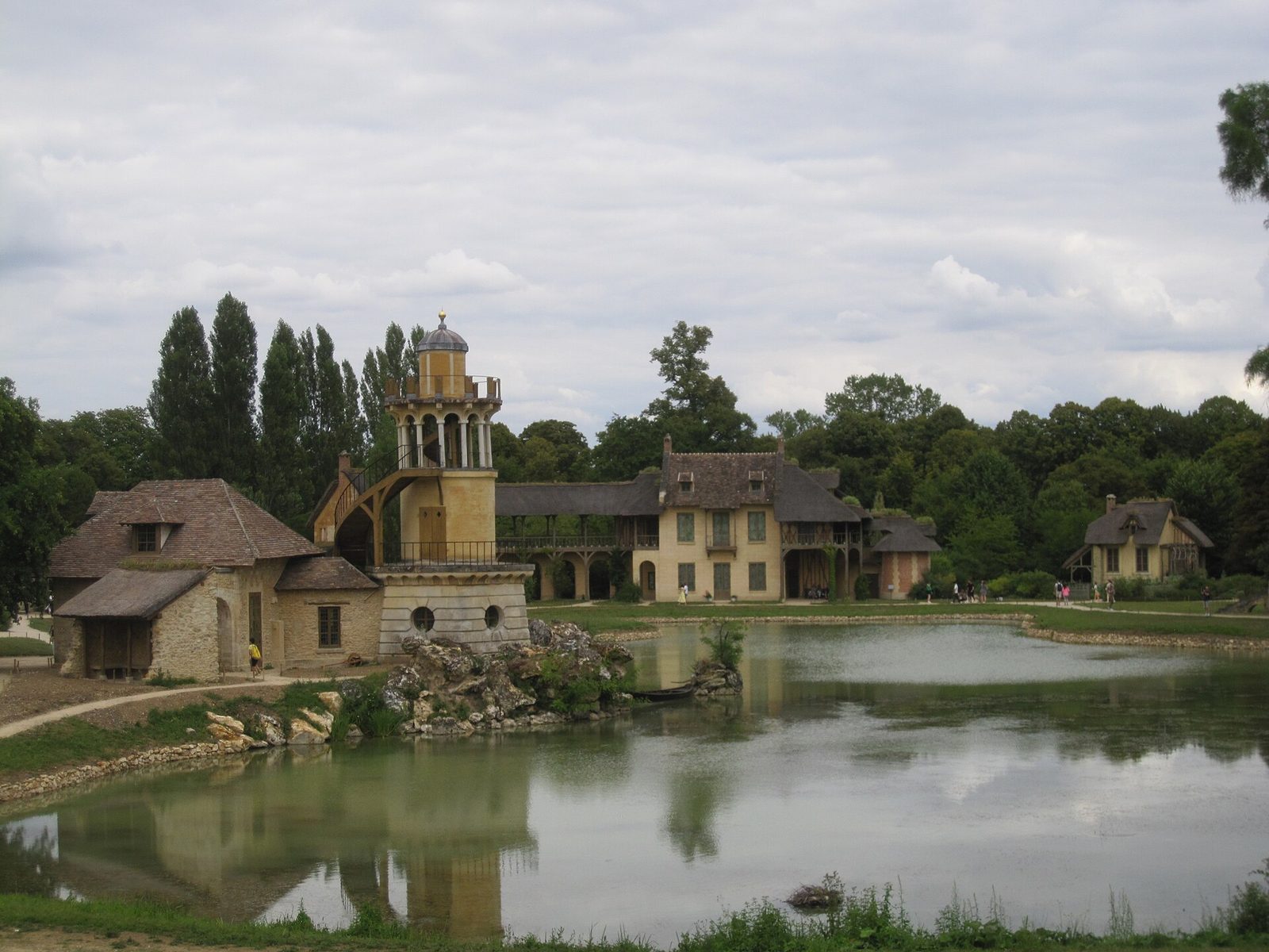Hameau de la Reine i Versailles med stråtekte hus, mølletårn og dam i forgrunnen