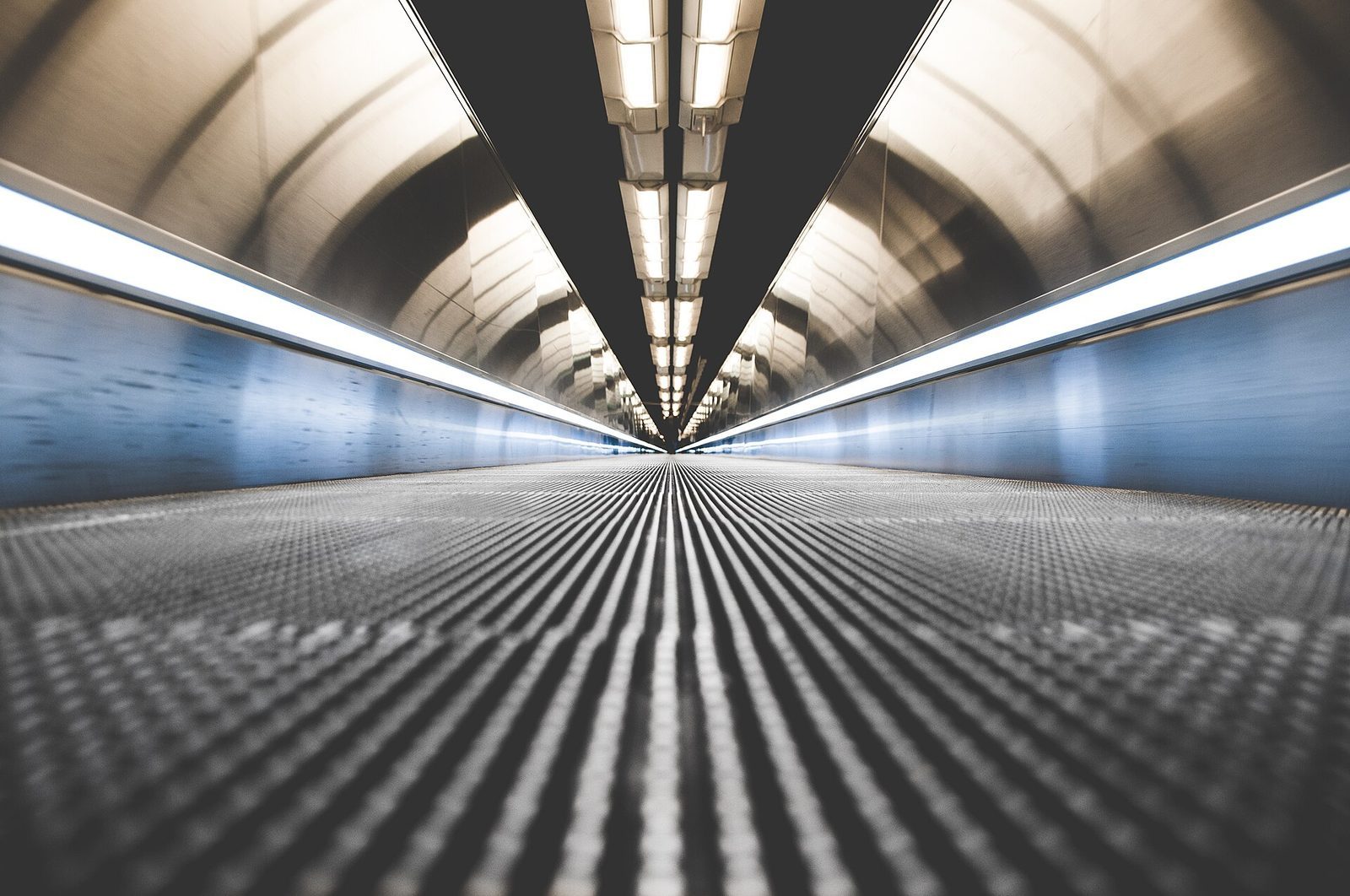 Lang rullende gangvei i en opplyst tunnel under en parisisk metrostasjon